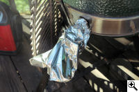 We fashioned this wind guard from aluminum foil to keep the breeze from feeding the fire.